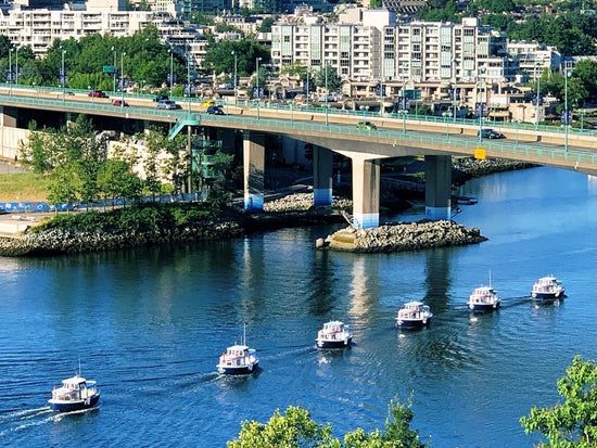 a line of ferries passing under a bridge
