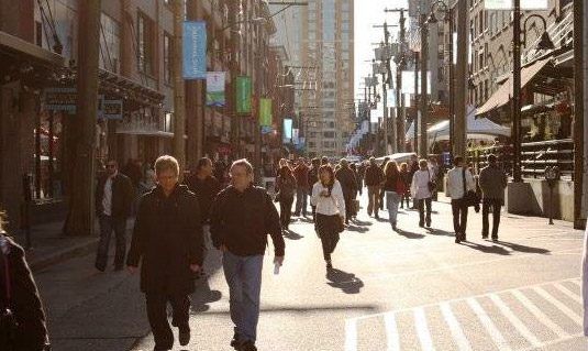 Pedestrians on a street lined with shops and restaurants